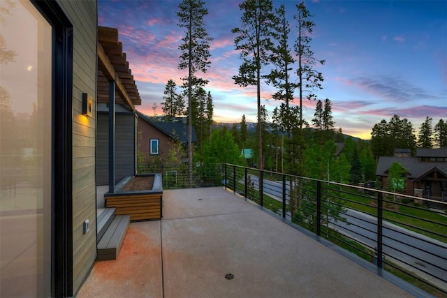 patio terrace at dusk featuring a balcony