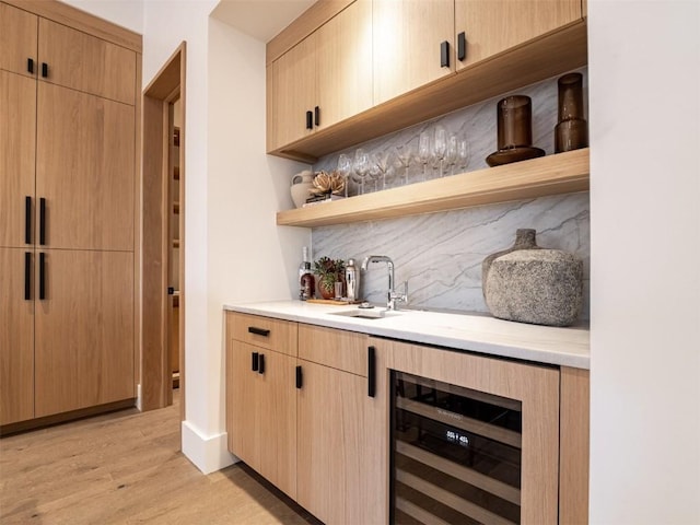 bar featuring light brown cabinets, wine cooler, and light hardwood / wood-style flooring