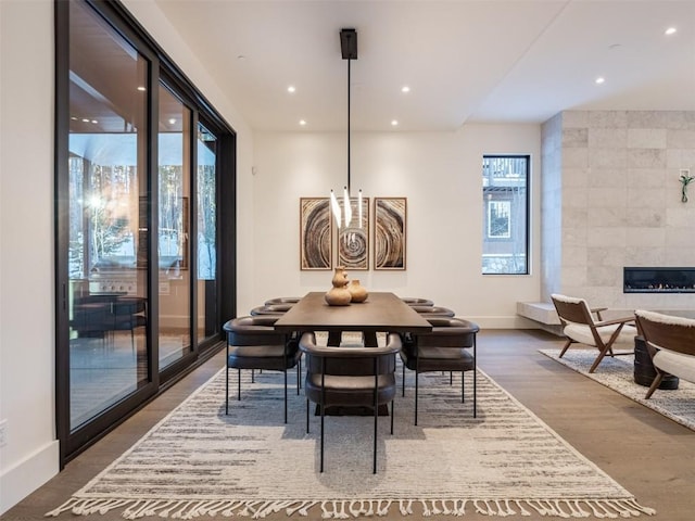 dining space with a healthy amount of sunlight, wood-type flooring, tile walls, and a tiled fireplace