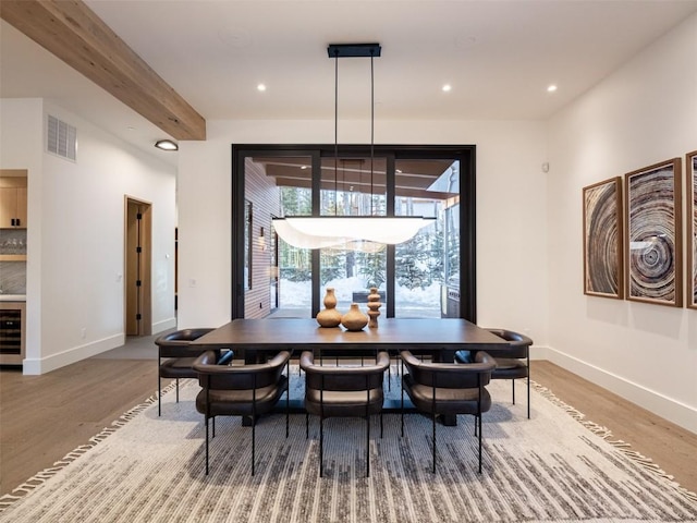 dining area featuring hardwood / wood-style floors, plenty of natural light, beamed ceiling, and beverage cooler