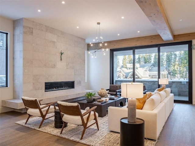 living room featuring a fireplace, tile walls, a notable chandelier, beamed ceiling, and light hardwood / wood-style floors