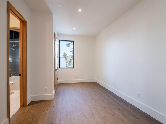 unfurnished bedroom featuring hardwood / wood-style flooring and ensuite bathroom