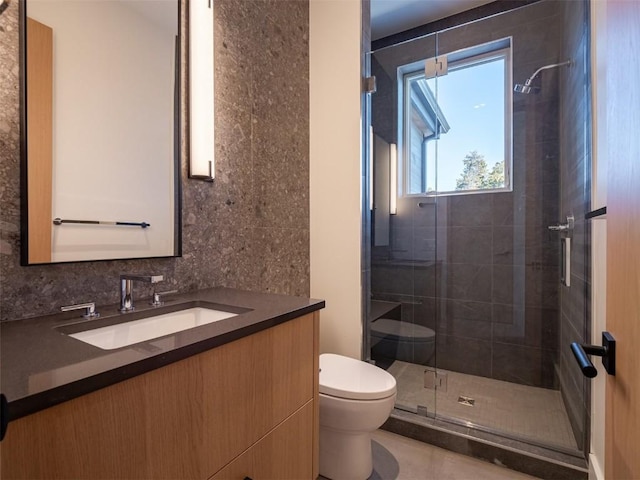 bathroom with decorative backsplash, vanity, a shower with shower door, and toilet