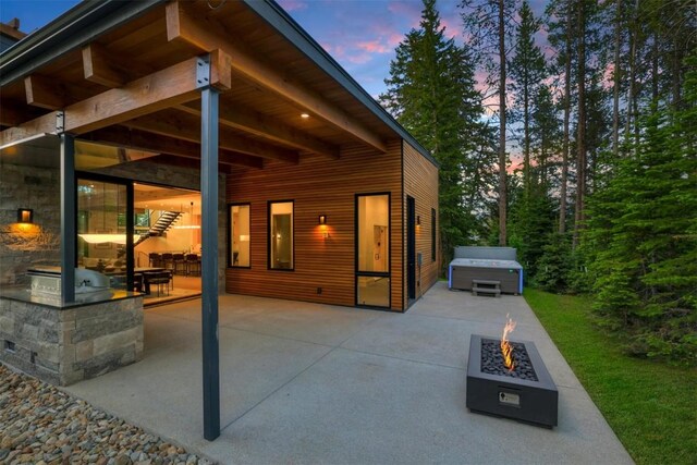 patio terrace at dusk with a fire pit and a hot tub