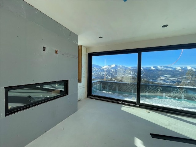 unfurnished room with a healthy amount of sunlight, finished concrete floors, and a mountain view