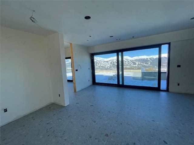 unfurnished room featuring plenty of natural light and a mountain view