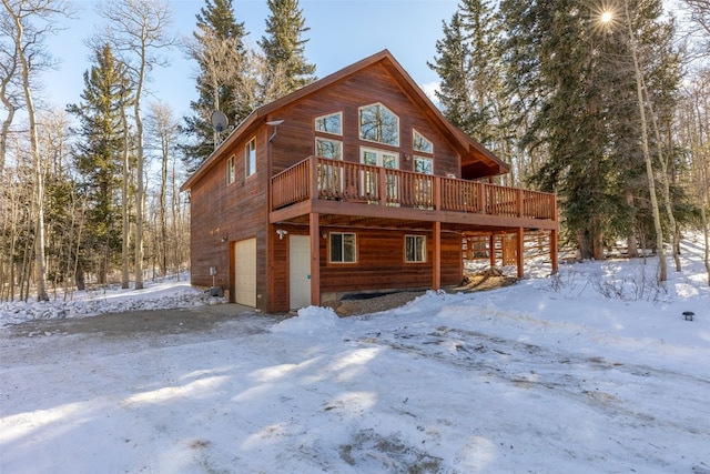 snow covered property with a deck and a garage