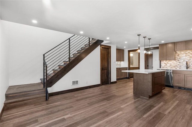 kitchen with pendant lighting, backsplash, a kitchen island, dark hardwood / wood-style flooring, and stainless steel dishwasher