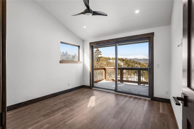 empty room featuring ceiling fan, dark hardwood / wood-style floors, a mountain view, and vaulted ceiling