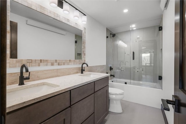 full bathroom with combined bath / shower with glass door, tile walls, vanity, tile patterned floors, and toilet