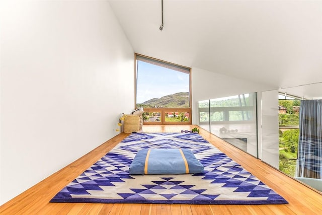 bedroom with expansive windows, basketball hoop, a mountain view, and hardwood / wood-style floors