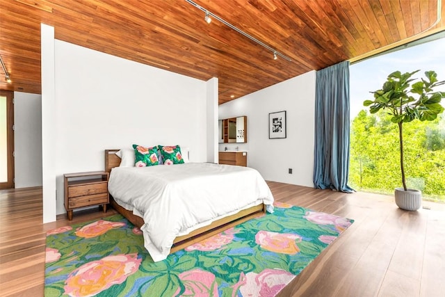 bedroom with wood ceiling, track lighting, floor to ceiling windows, and hardwood / wood-style flooring