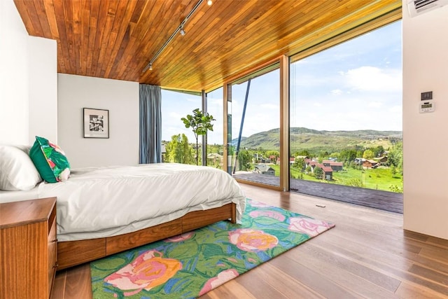 bedroom with access to exterior, wood ceiling, track lighting, and a wall of windows