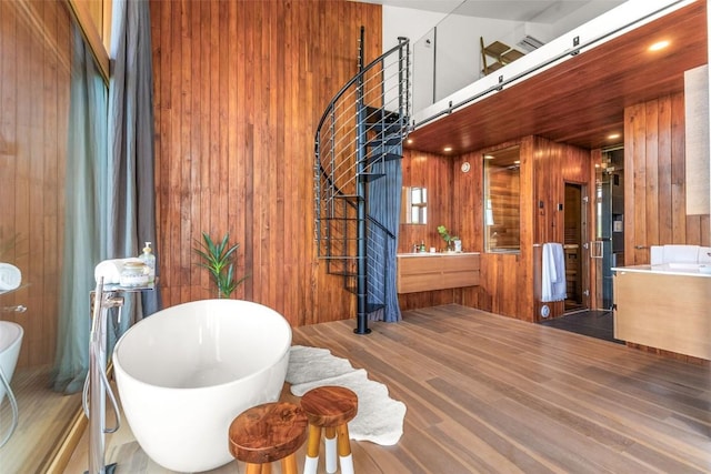 bathroom featuring hardwood / wood-style floors, vanity, a bath, and wood walls