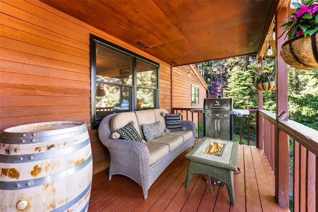 deck with grilling area and an outdoor living space with a fire pit