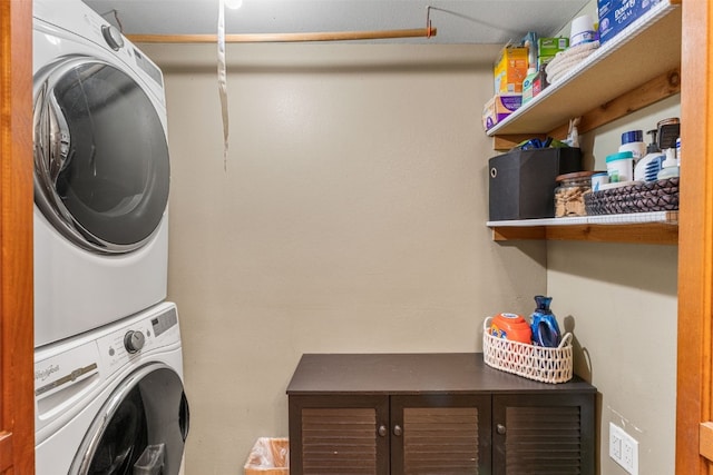 laundry area featuring stacked washer / dryer and cabinets