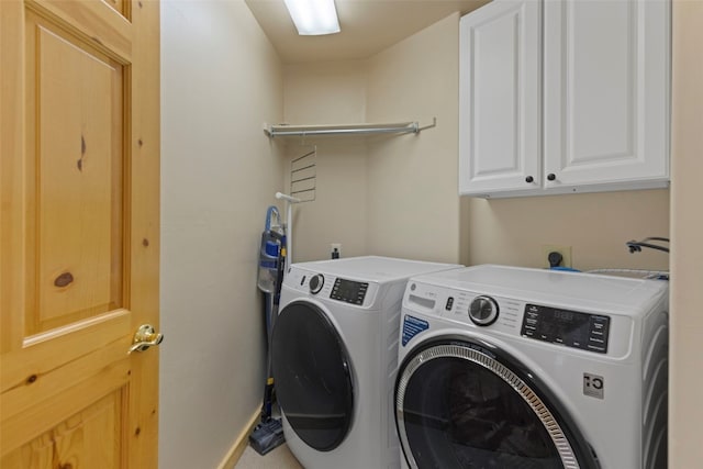 laundry area with independent washer and dryer and cabinets