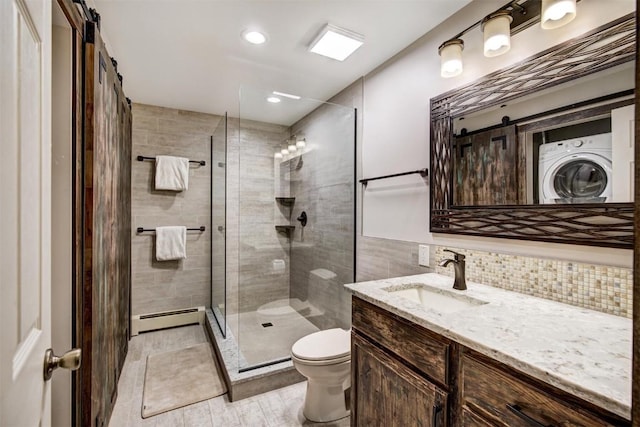 bathroom with walk in shower, vanity, baseboard heating, washer / clothes dryer, and toilet