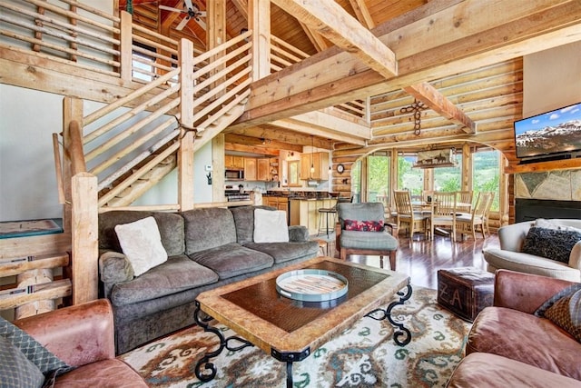 living room with beam ceiling, rustic walls, wooden ceiling, high vaulted ceiling, and hardwood / wood-style flooring