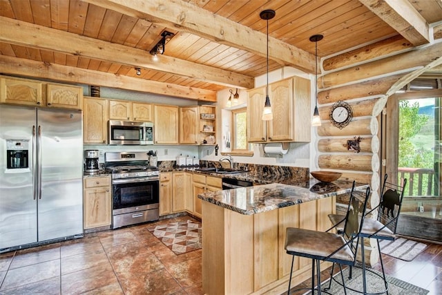 kitchen featuring kitchen peninsula, appliances with stainless steel finishes, rustic walls, dark stone counters, and decorative light fixtures