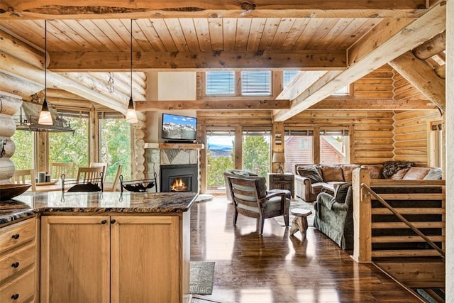 kitchen featuring rustic walls, wooden ceiling, a stone fireplace, dark stone countertops, and decorative light fixtures