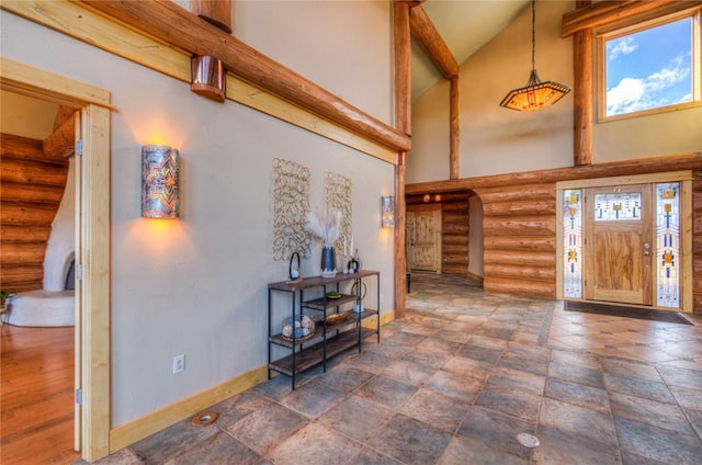 foyer entrance with a towering ceiling and log walls