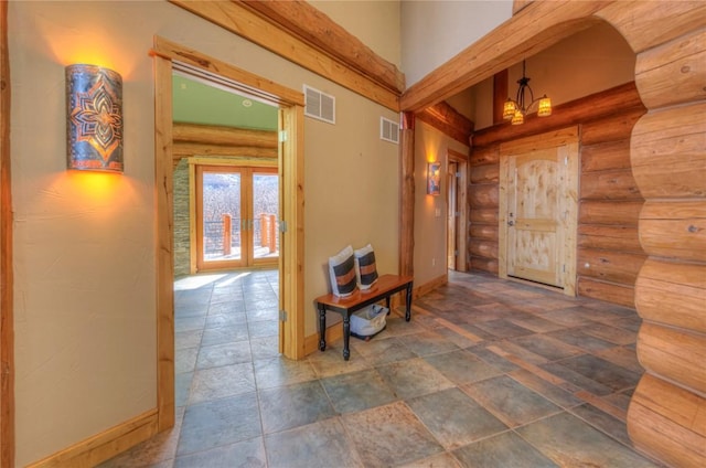 hall featuring rustic walls, french doors, and a notable chandelier