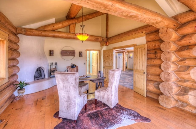 interior space featuring a fireplace, light hardwood / wood-style flooring, log walls, and high vaulted ceiling