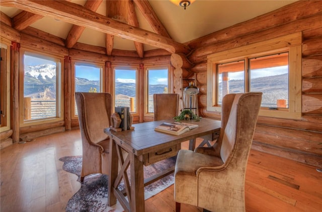 dining room featuring a mountain view, vaulted ceiling, log walls, and light hardwood / wood-style flooring