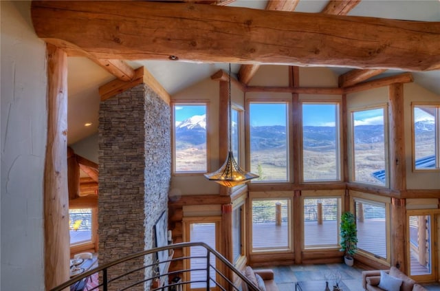 unfurnished living room featuring a mountain view, beam ceiling, and high vaulted ceiling