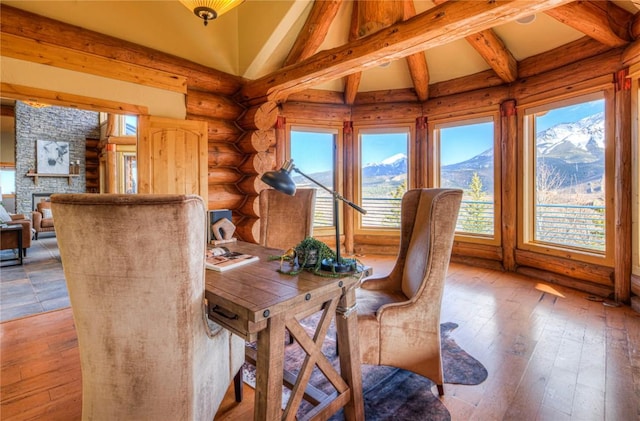 dining space with a mountain view, lofted ceiling, a stone fireplace, light hardwood / wood-style flooring, and log walls