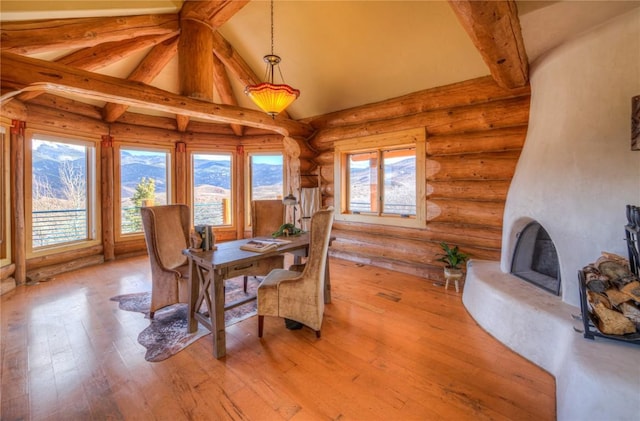 dining area featuring lofted ceiling with beams, light wood-type flooring, rustic walls, and a wealth of natural light