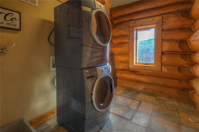 washroom with rustic walls and stacked washer and dryer