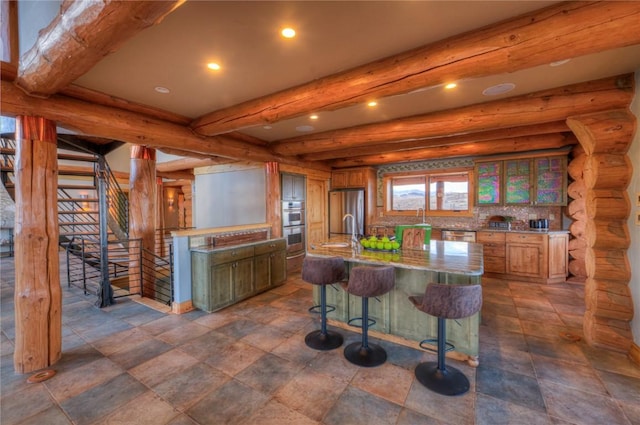 kitchen with log walls, stainless steel appliances, beamed ceiling, a spacious island, and a kitchen bar