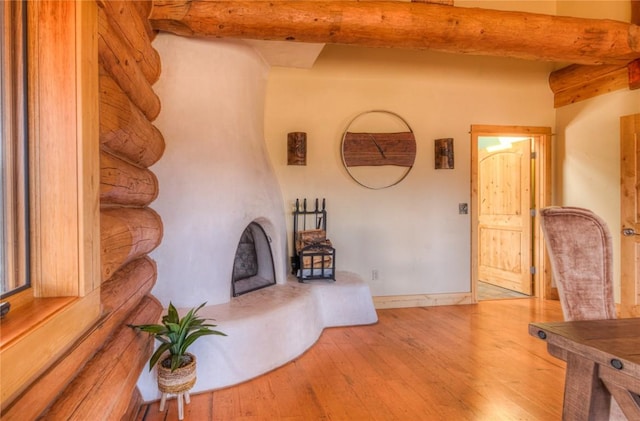 living room with log walls, light wood-type flooring, and beamed ceiling