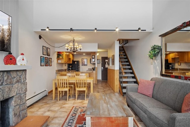 living room featuring a fireplace, baseboard heating, and a chandelier