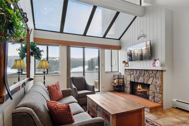 living room with wood walls, a fireplace, a baseboard radiator, and a high ceiling