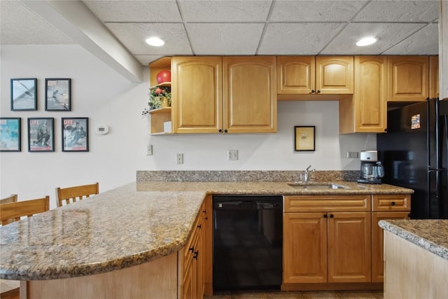 kitchen featuring kitchen peninsula, a kitchen bar, light stone countertops, sink, and black appliances