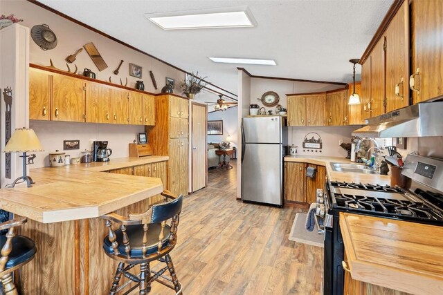 kitchen with hanging light fixtures, stainless steel appliances, kitchen peninsula, crown molding, and a breakfast bar area