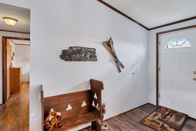 foyer with dark wood-type flooring, a textured ceiling, and ornamental molding