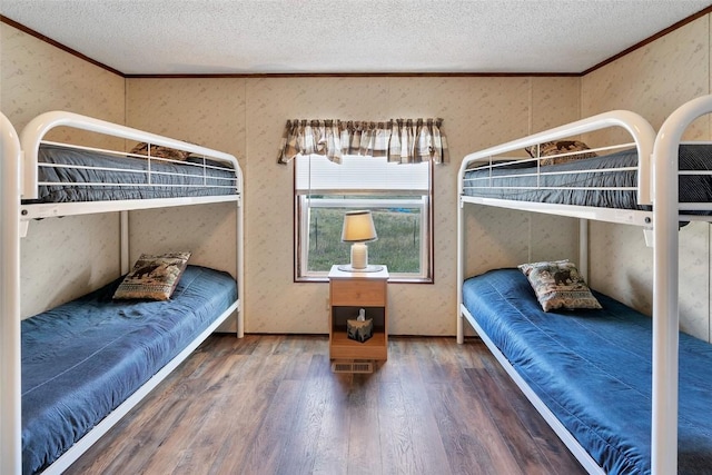 bedroom with a textured ceiling, dark hardwood / wood-style floors, and crown molding