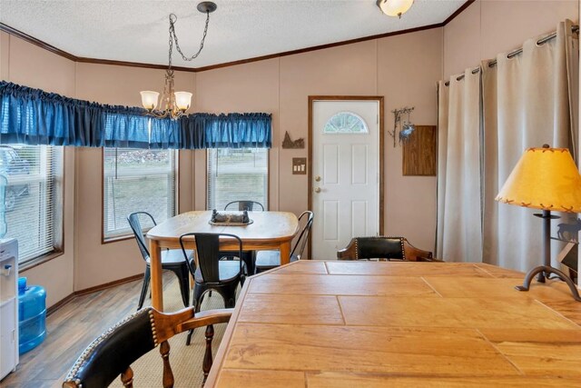 dining room featuring a textured ceiling, hardwood / wood-style flooring, an inviting chandelier, and crown molding