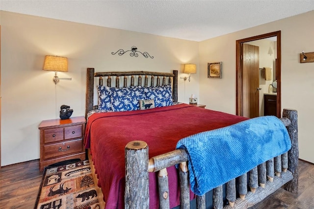 bedroom featuring dark hardwood / wood-style flooring, a textured ceiling, and connected bathroom