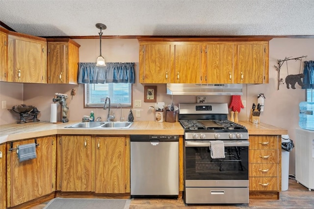 kitchen featuring pendant lighting, sink, light hardwood / wood-style flooring, a textured ceiling, and stainless steel appliances