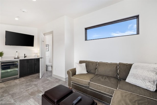 living room with beverage cooler, baseboards, and wet bar