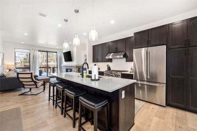 kitchen with visible vents, high quality fridge, open floor plan, under cabinet range hood, and a sink