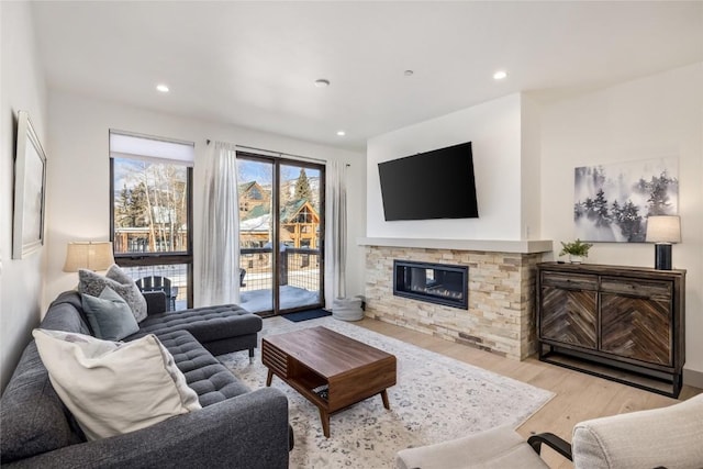 living area featuring recessed lighting, a stone fireplace, and wood finished floors