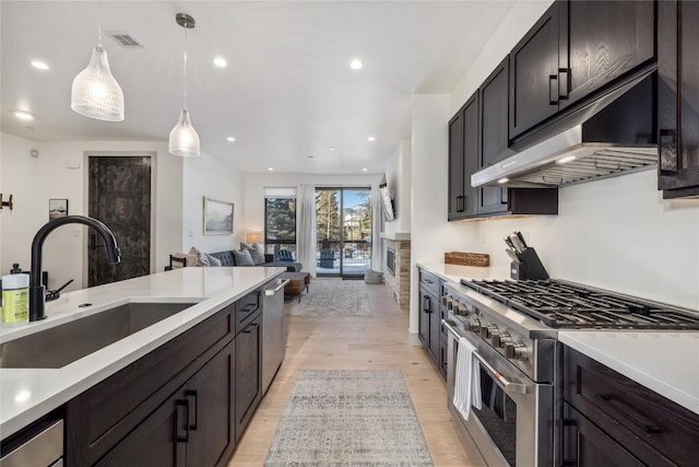 kitchen featuring visible vents, decorative light fixtures, stainless steel appliances, under cabinet range hood, and a sink