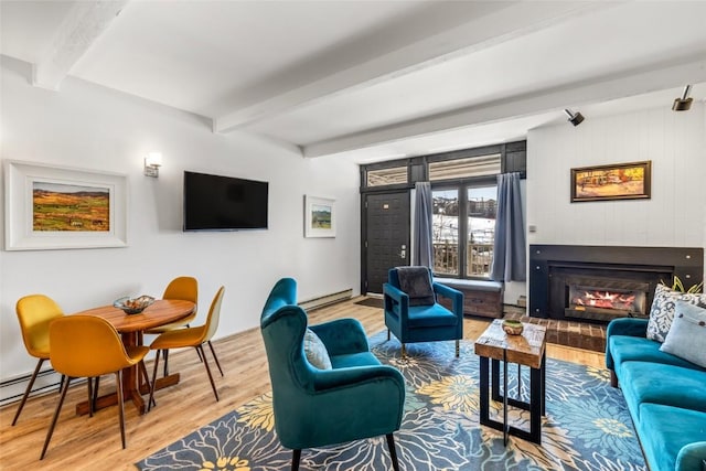 living area with a glass covered fireplace, a baseboard heating unit, beam ceiling, and wood finished floors