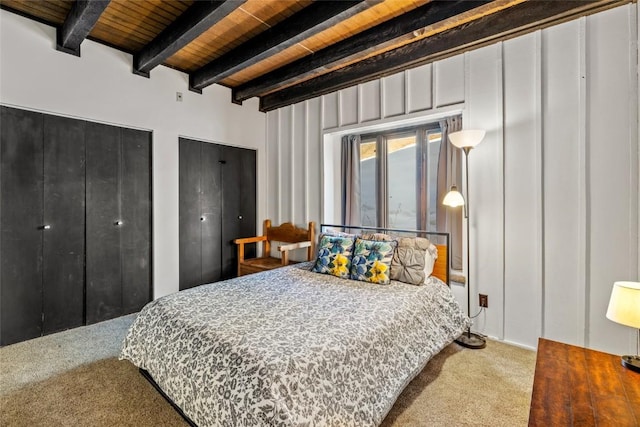 bedroom with beamed ceiling, multiple closets, wooden ceiling, and carpet flooring